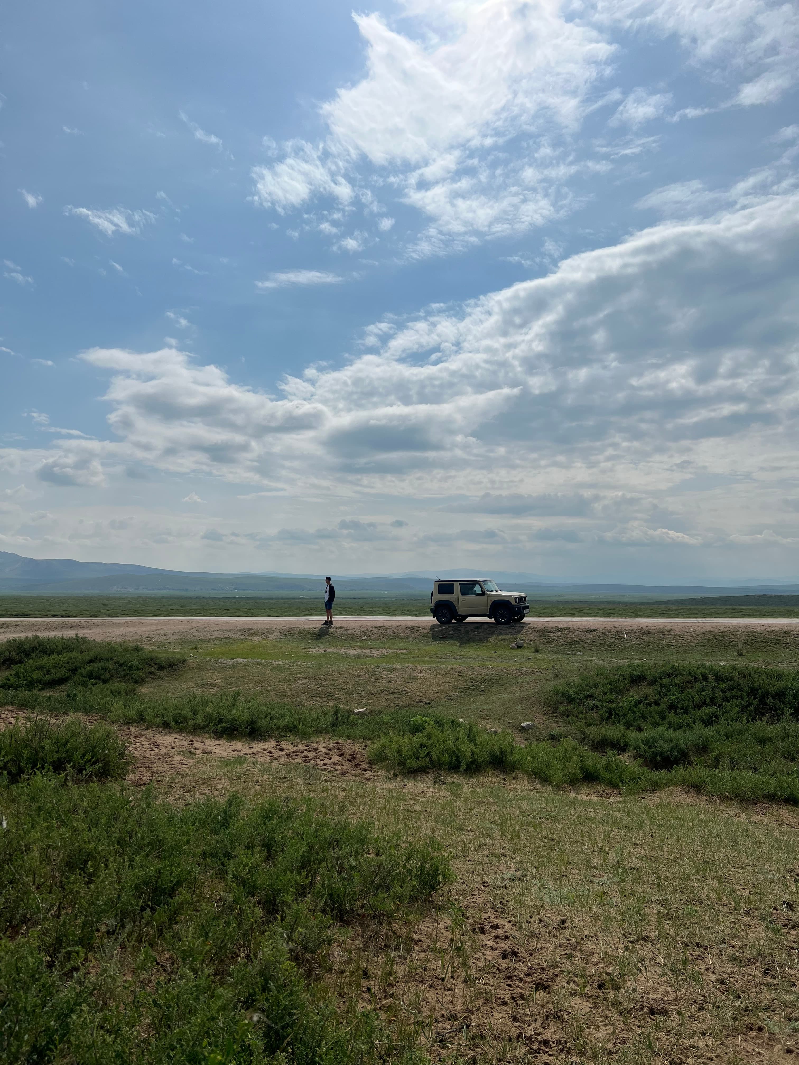 A vehicle stopped on a paved road across the open steppe in Bulgan province, Mongolia.