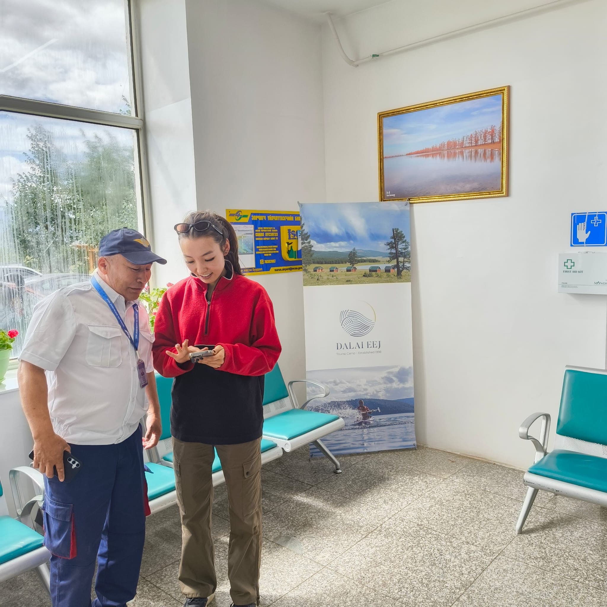 Travelers in the Murun Airport terminal with Dalai Eej Resort signage visible.